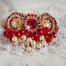 Broche Rubis brod&eacute;e avec trois cabochons Ivoire et Rouge &agrave; laquelle s&rsquo;ajoute des toupies aux couleurs Cristal, Burgundy et Garnet, des perles nacr&eacute;es et opaque. Mont&eacute; sur une dentelle et une broche